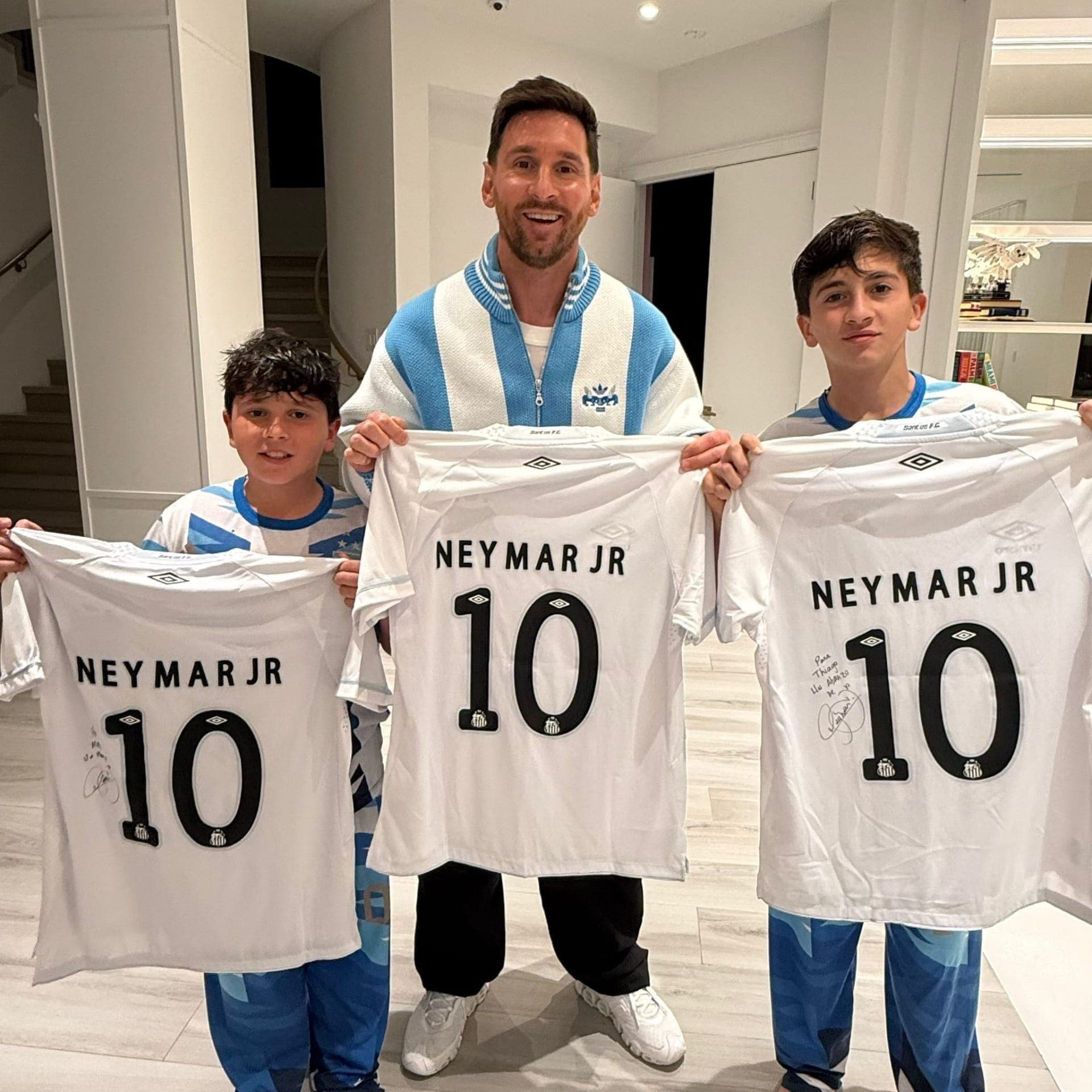 Mateo, Lionel e Thiago Messi com as camisas presenteadas pelo Santos